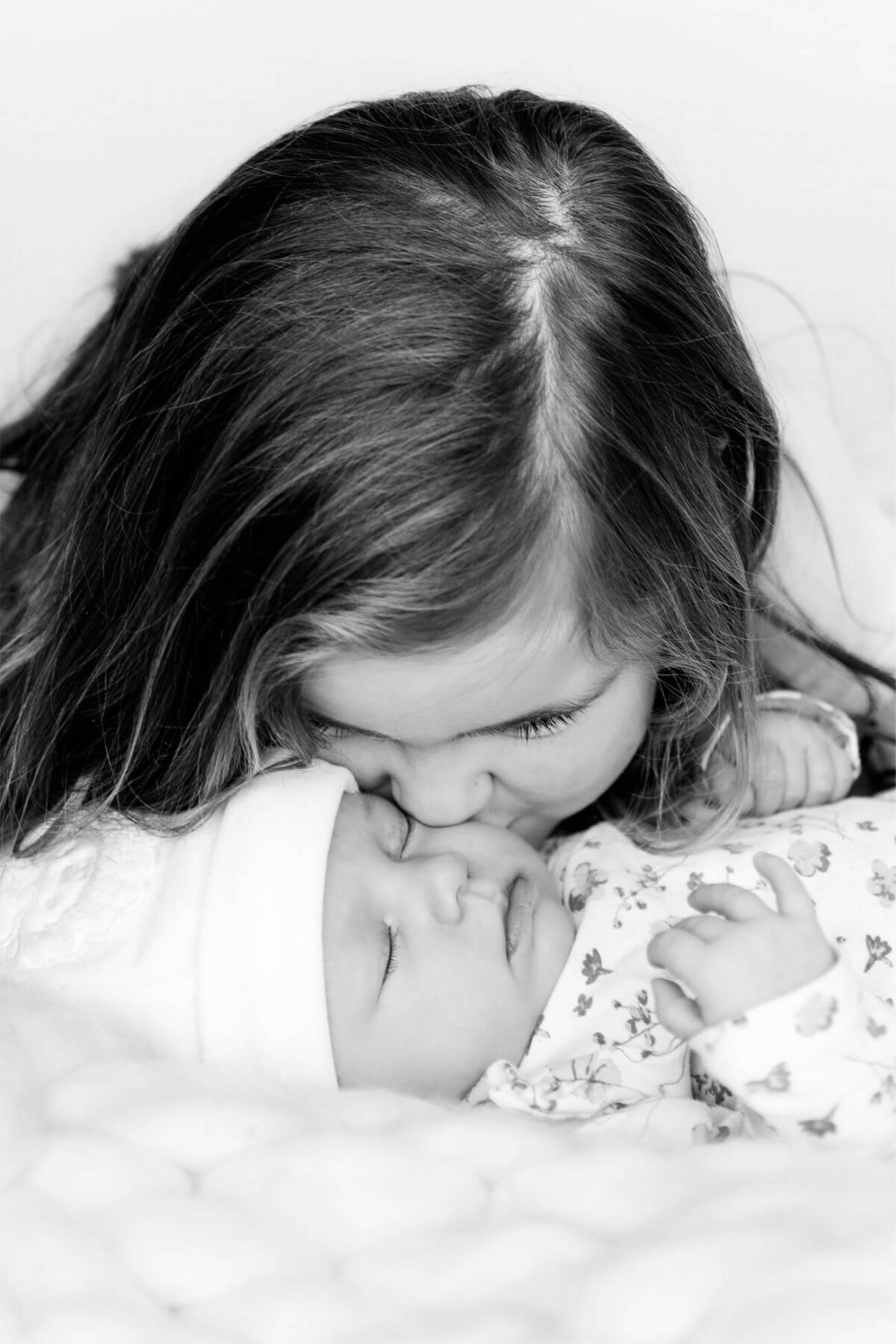Meisje geeft haar babyzusje een kus