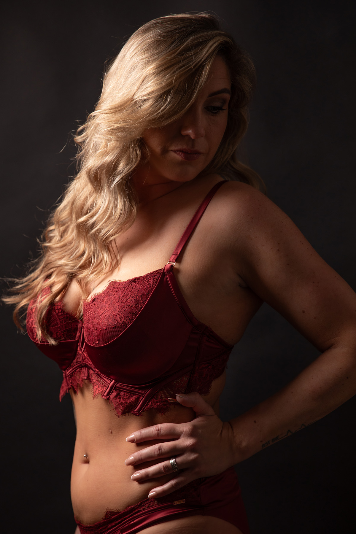 Vrouw in rode lingerie tijdens een stijlvolle boudoirshoot