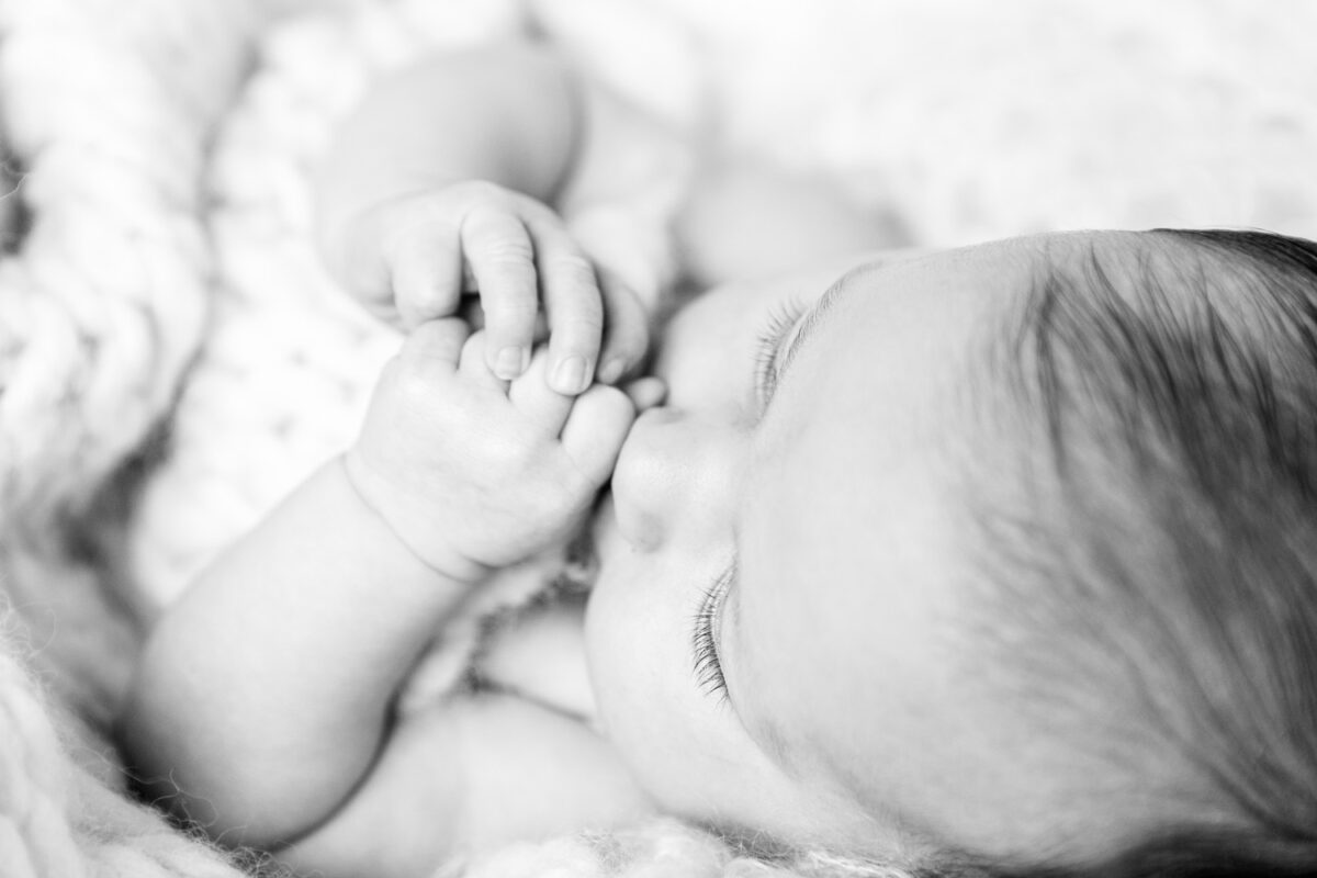 pasgeboren baby met handjes in de mond