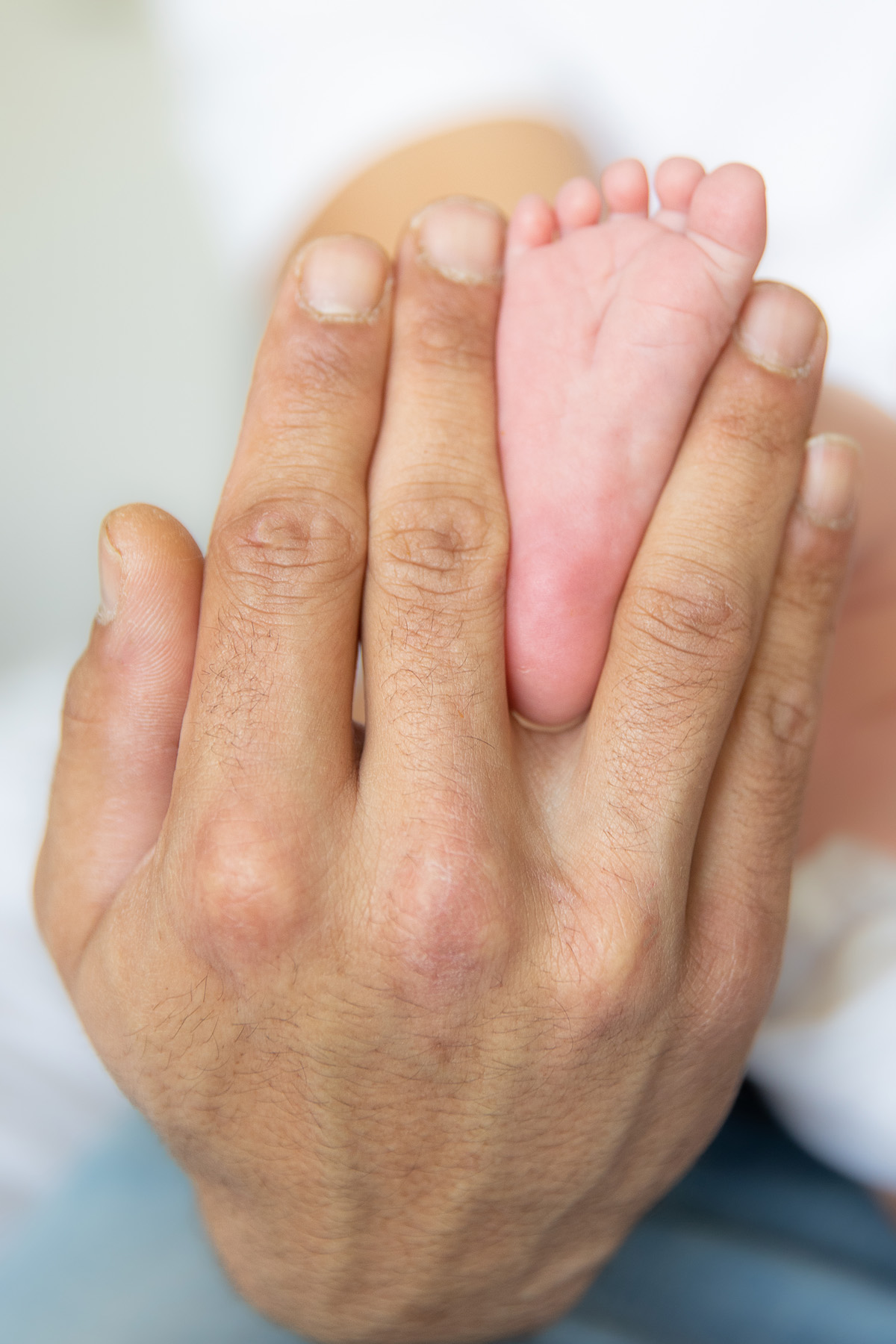 Hand van ouder naast de voetjes van een pasgeboren baby