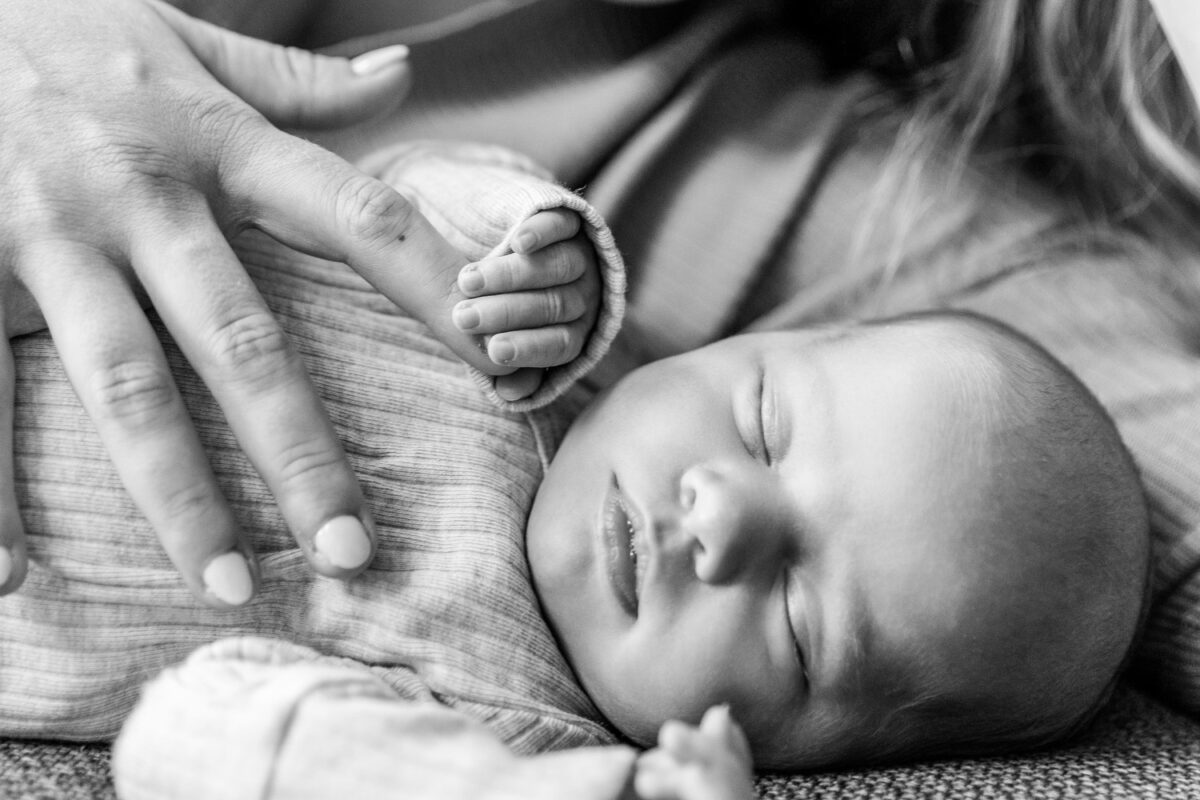 Hand van ouder met de hand van een pasgeboren baby