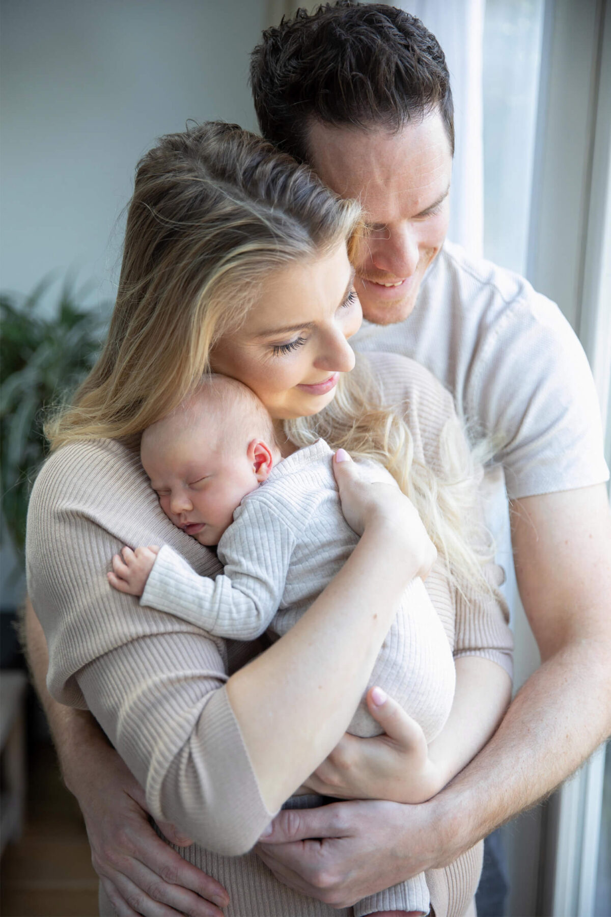 Ouders met hun pasgeboren baby bij het raam