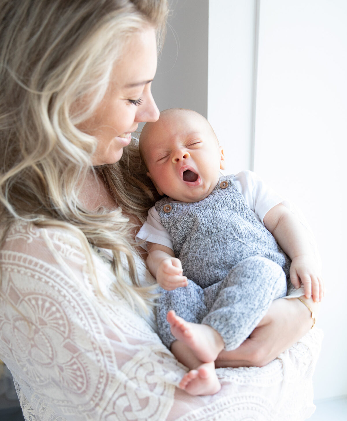 moeder met geeuwende baby bij het raam