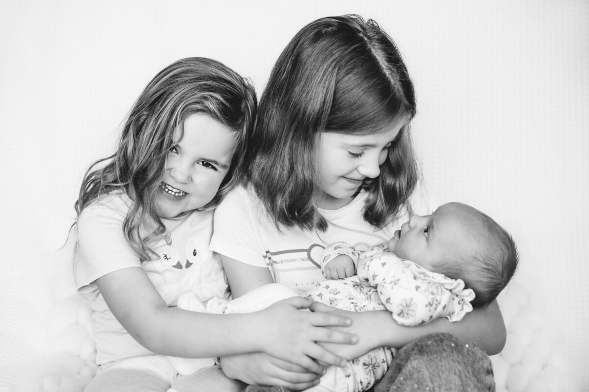 Twee kinderen met hun pasgeboren babyzusje