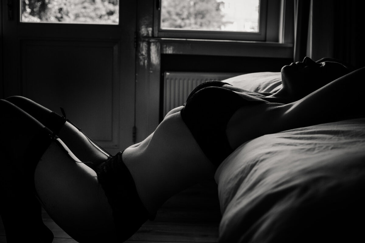 Vrouw in zwarte lingerie liggend op bed